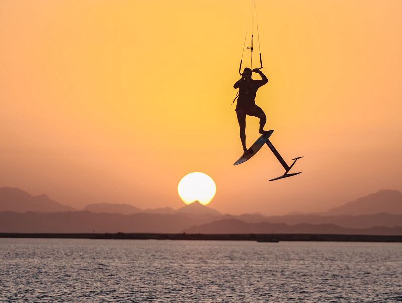 Kiter flying on a hydrofoil above the water at sunset