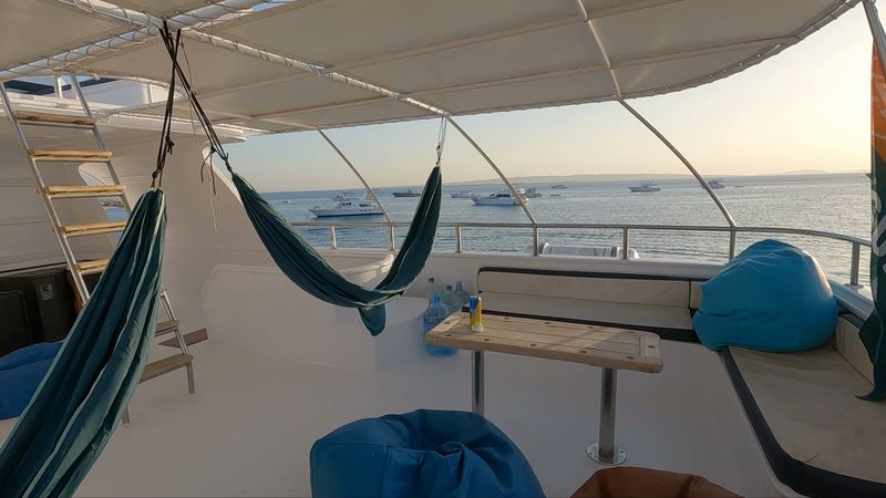The yacht's upper deck with a hammock and bean bags in the evening light