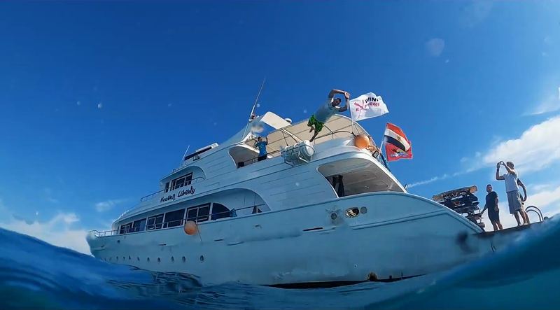 The yacht with guests on deck, a half-underwater shot