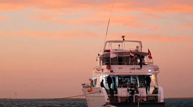 The safari yacht at anchor under an orange sunset sky