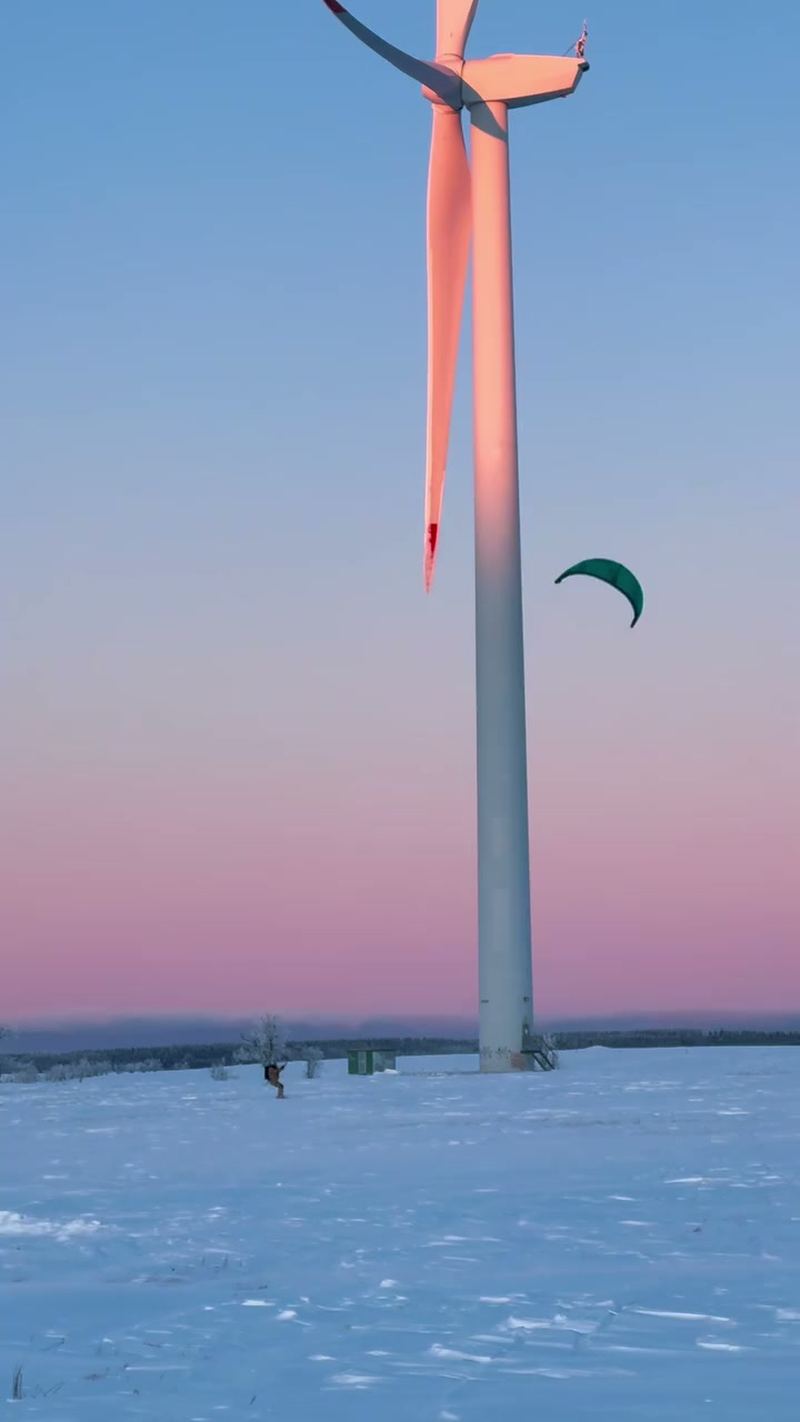 Snowkiting at sunset in the Ore Mountains, a kite next to a wind turbine