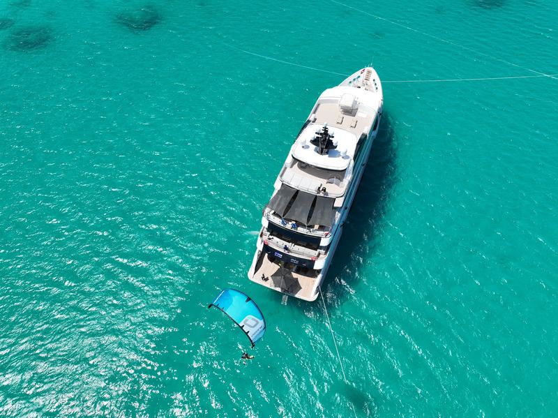 Yacht from above in turquoise water with a kite