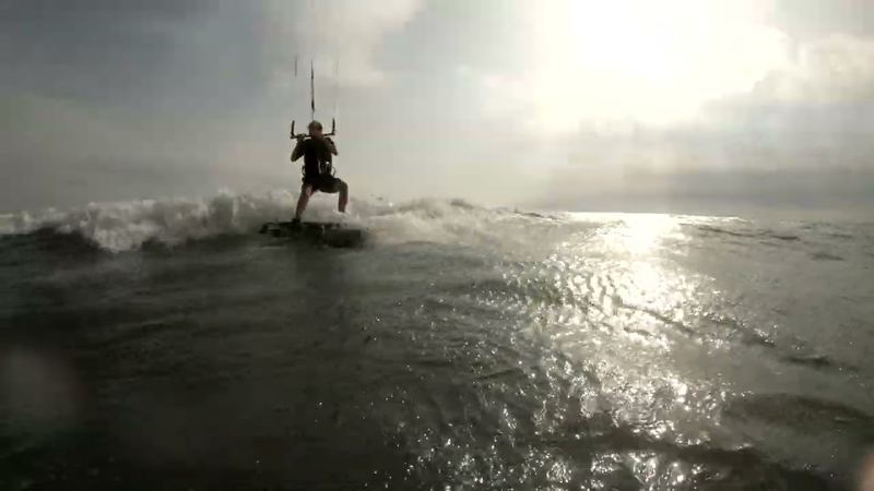 Kiter riding a wave against the light in Sicily