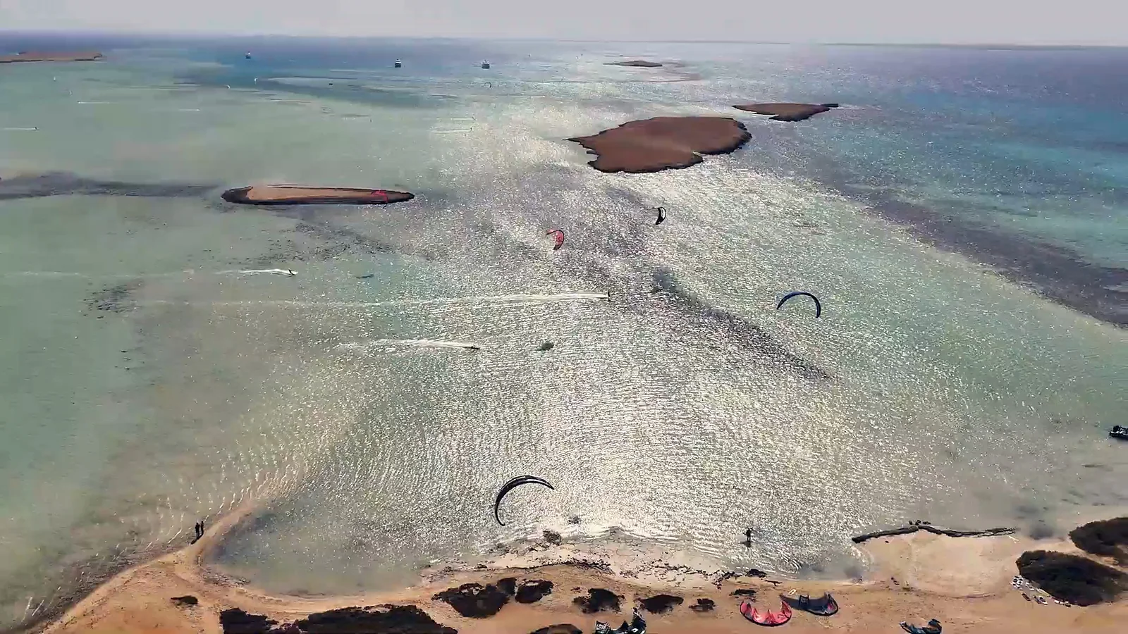 A shallow lagoon with kites, the water glittering in the sun