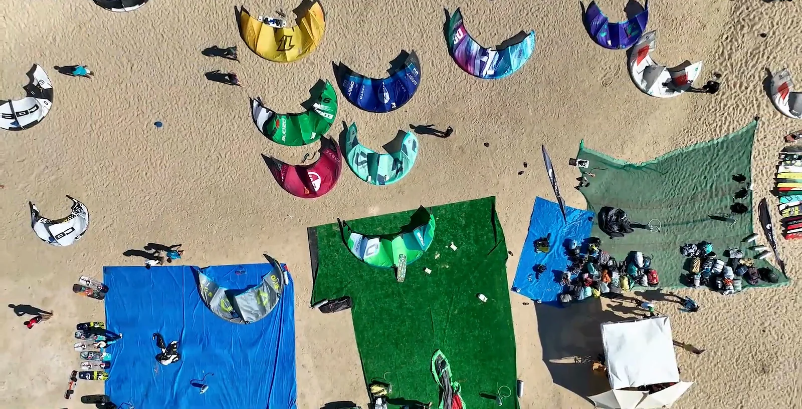 Colourful kites laid out on the sand, seen from above